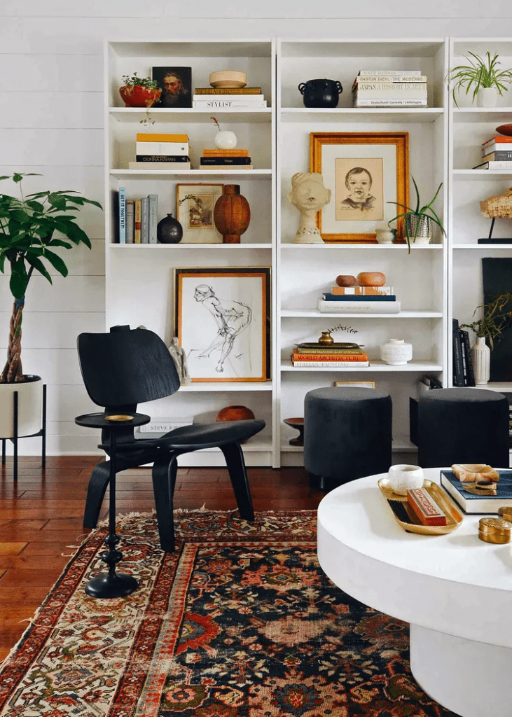 white-book-shelves-antique-area-rug-black-modern-chair-in-a-eclectic-living-room
